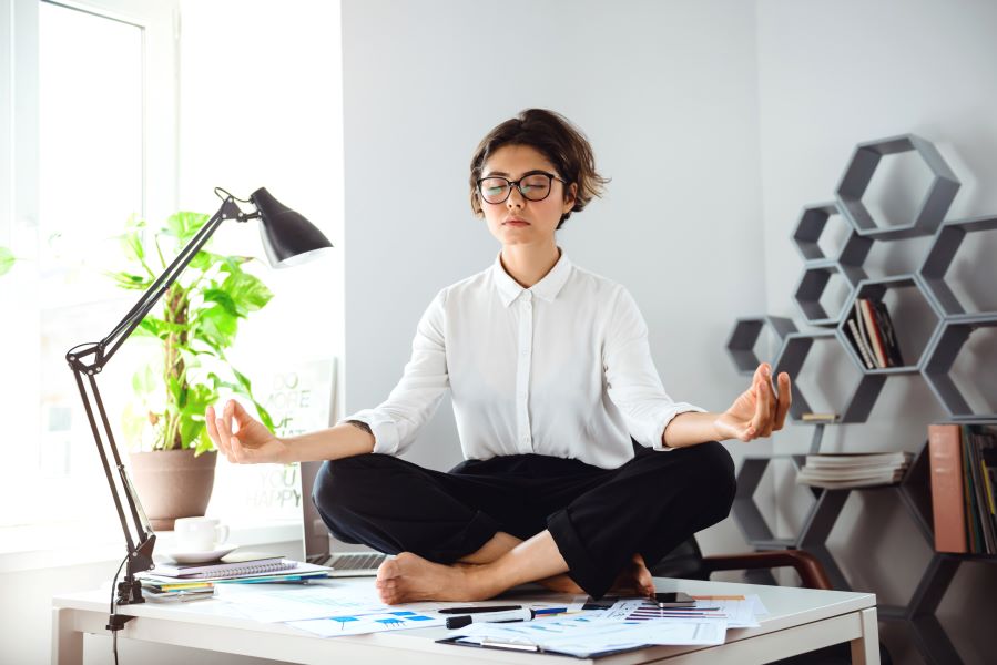 belle-jeune-femme-d-affaires-meditant-sur-table-au-lieu-de-travail-au-bureau